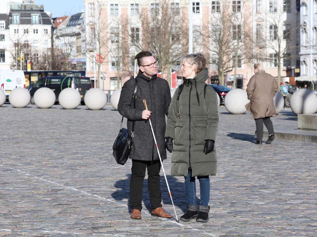 Døvblind mand med hvid stok og kontaktperson på Christiansborg slotsplads