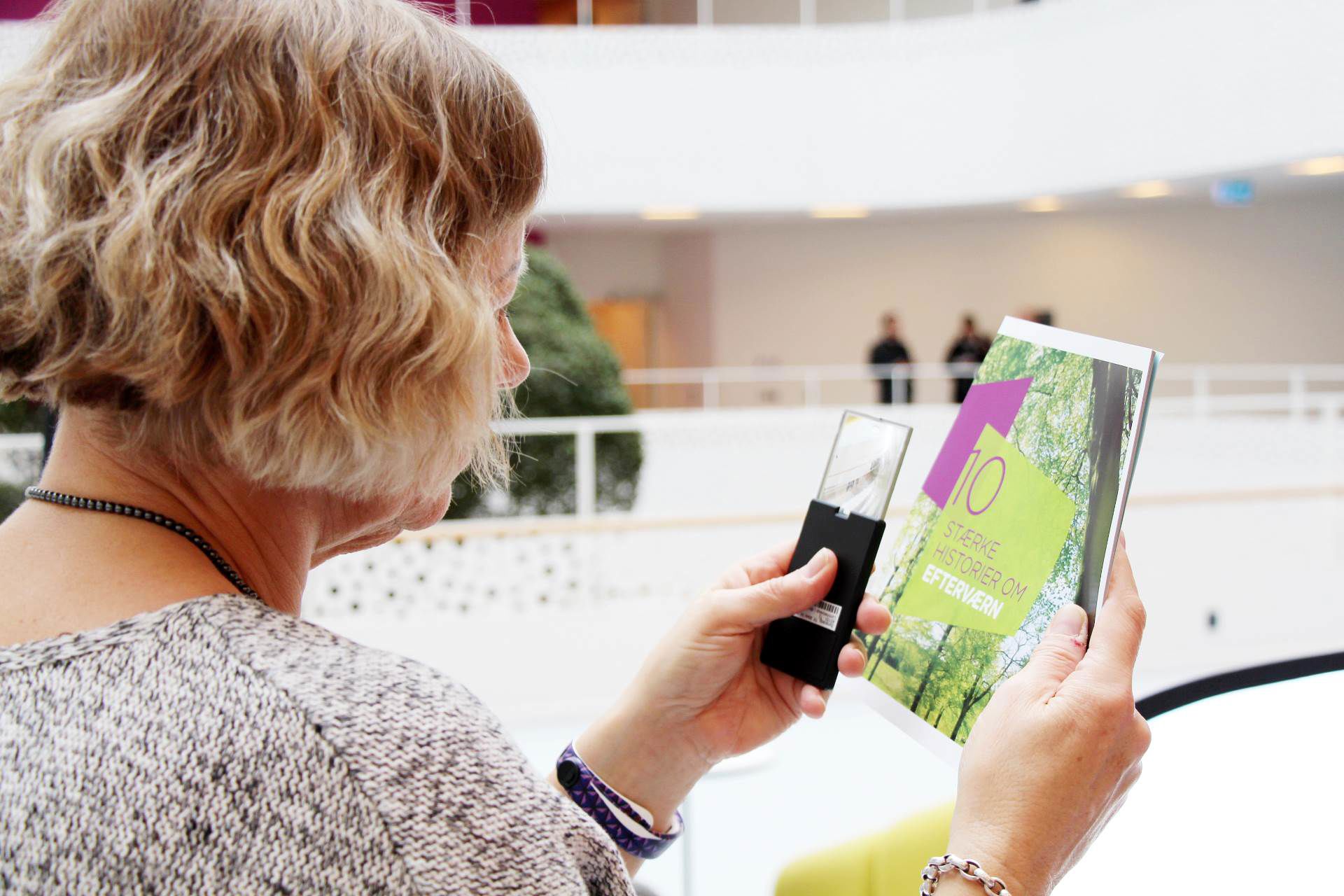 Døvblind kvinde læser pjece med lup