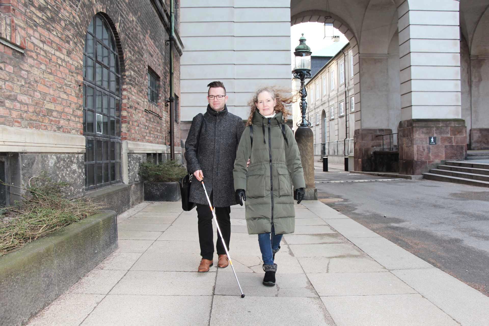 Ung døvblind mand med hvid stok ledsages af sin kontaktperson