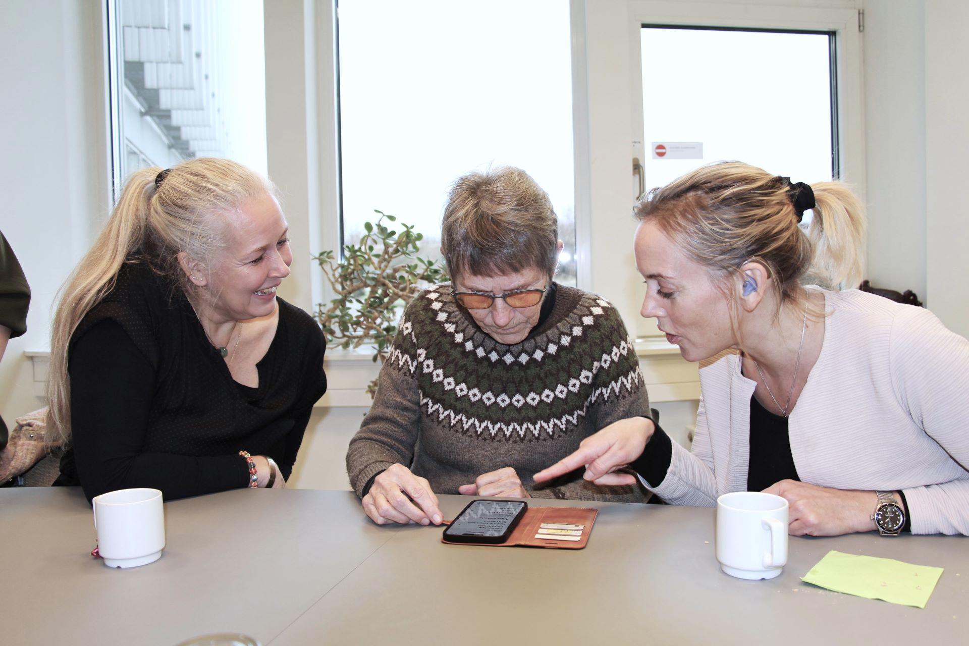Tre kvinder snakker og rådgiver hinanden om en app på mobiltelefon